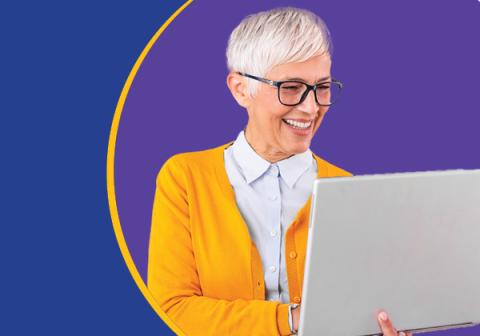 Photo of a woman in a yellow sweater holding a laptop computer